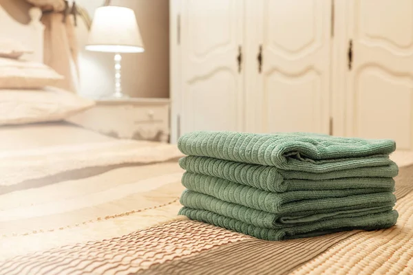 Stack of green hotel towel on bed in bedroom interior - Image