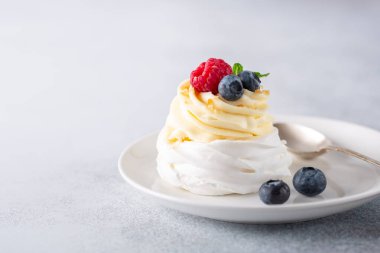 Krem şantili ve beyaz tabakta taze böğürtlenli lezzetli Pavlova pastası. Taş zemin. Seçici odak
