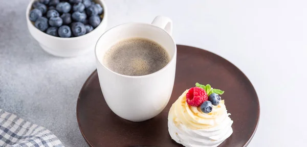 Romantisches Frühlingsfrühstück. Leckerer Pavlova-Kuchen mit Sahne und frischen Beeren und Kaffeebecher. Weicher Fokus — Stockfoto