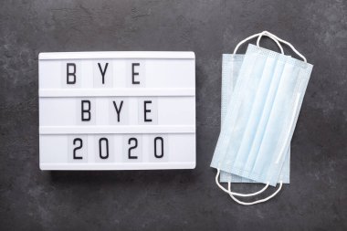 Elveda mesajı içeren ışık kutusu. 2020, karanlık arka planda tıbbi maske. Üst Manzara. Yeni yıl kutlaması. Mutlu yıllar 2021 kavramları - Görüntü