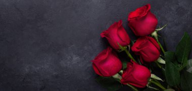 Siyah taş arkaplanda kırmızı gül buketi Sevgililer Günü tebrik kartı. Boşluğu kopyala. Yatay afiş yatar.