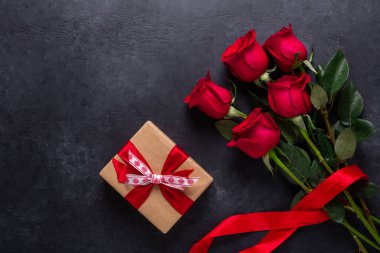 Kırmızı gül buketi ve hediye kutusu siyah taş zemin üzerinde Sevgililer Günü tebrik kartı kopyalama alanı düz yatıyordu