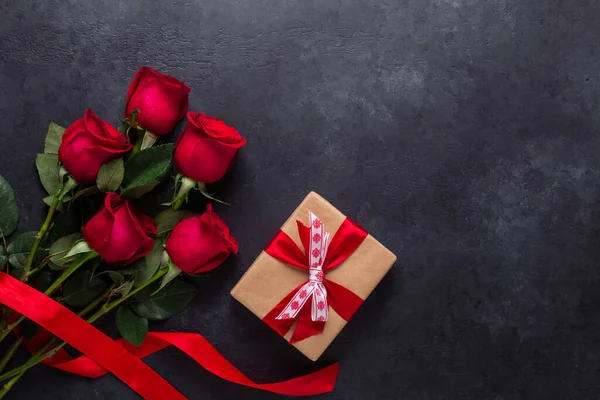 Kırmızı gül buketi ve hediye kutusu siyah taş zemin üzerinde Sevgililer Günü tebrik kartı kopyalama alanı düz yatıyordu