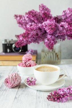 Bir buket leylak, bir fincan kahve, ev yapımı marşmelov ve kitap yığını Retro kamera Seçici odak