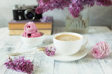 Bir buket leylak, bir fincan kahve, ev yapımı marşmelov ve kitap yığını Retro kamera Seçici odak