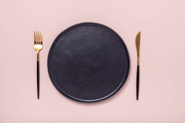 Siyah seramik tabak, çatal ve bıçak pastel pembe arka planda. Üst Manzara. Metin için yer - Resim