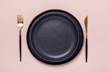 Pastel pembe arka planda iki boş seramik tabak ve çatal bıçak takımı. Metnin için alanı kopyala - Resim
