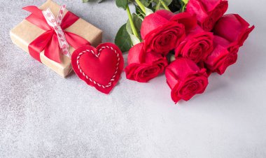 Güzel kırmızı güller, hediye kutusu ve taş arka planda dekoratif tekstil kalbi. Sevgililer Günü konsepti