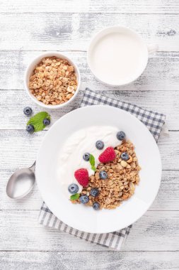 Yoğurtlu ev yapımı granola ve ahşap zemin üzerinde beyaz seramik tabakta taze böğürtlen.
