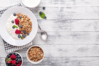 Yoğurtlu ev yapımı granola ve ahşap zemin üzerinde beyaz seramik tabakta taze böğürtlen. Boşluğu kopyala