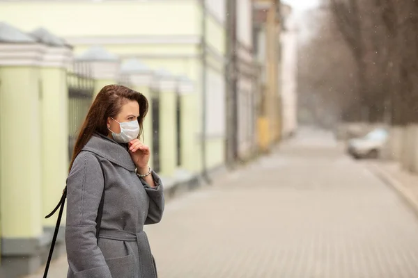 Kvinna bär skyddande medicinsk mask en tom europeisk gata, utomhus. Begreppet egenvård — Stockfoto