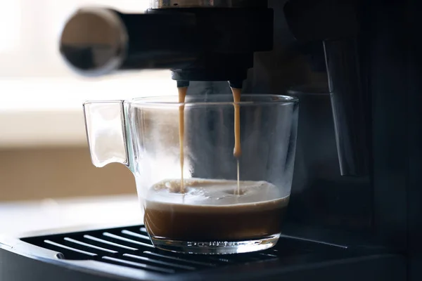 Coffee machine making espresso in glass transparent coffee cup. Hot espresso running into cup
