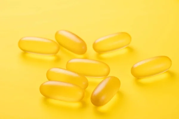 Close up Omega 3 capsules on yellow background. Fish oil softgels. Supplement food vitamin D capsules — Stock Photo, Image