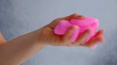 Beyaz arka planda pembe sümükle oynayan kadın elleri. Modaya uygun sıvı oyuncak. Üst görünüm