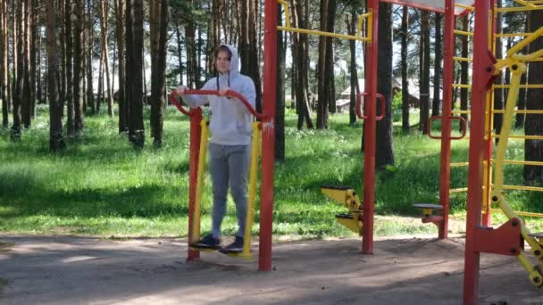 Hombre joven soltero haciendo ejercicios en la calle aparato de gimnasio en el parque, entrenamiento en la calle. Fitness afuera. Ejercicio solo para la prevención de Covid-19 — Vídeos de Stock