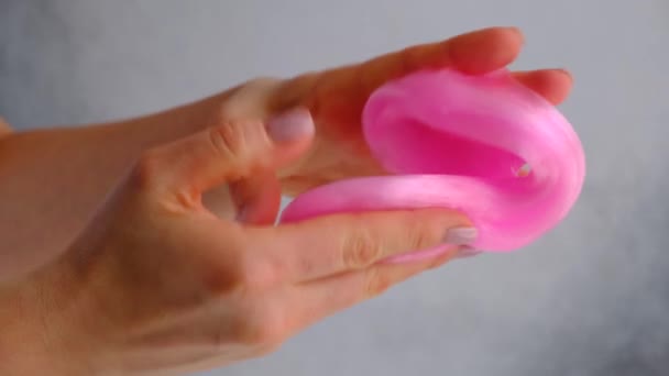 Kobiece ręce bawiące się różowym śluzem na białym tle. Modna płynna zabawka. Widok z góry — Wideo stockowe