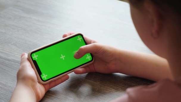 小女孩在他的智能手机上玩着色键绿色屏幕的游戏，敲打着展示。俄罗斯Vologda - 2021年4月15日 — 图库视频影像