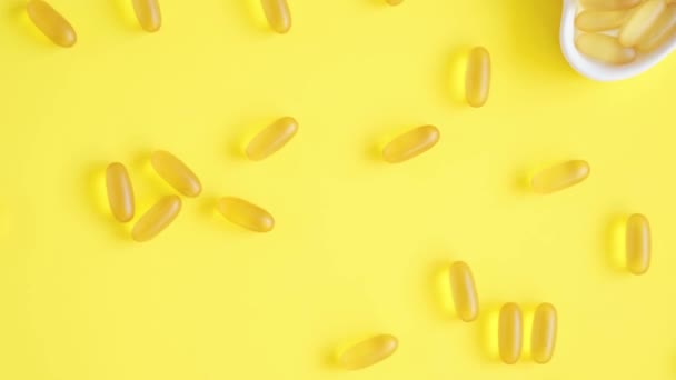 Vitamina D e Omega 3 capsule di olio di pesce supplemento in un piatto a forma di cuore su sfondo giallo. Concetto di sanità. Vista dall'alto — Video Stock