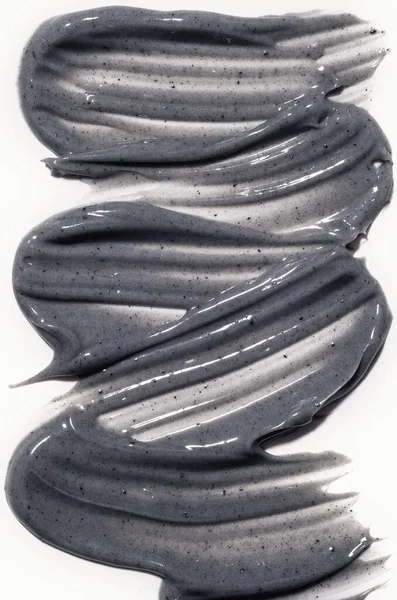 Kil ya da kömür maskesi vuruşu beyaza izole edilmiş. Yüz ve vücut için gri kozmetik maske. Dikey