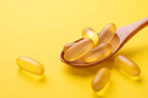 Κλείστε τις κάψουλες Omega 3 σε ξύλινη κουτάλα σε κίτρινο φόντο. Μαλακό λάδι ψαριού. Συμπλήρωμα κάψουλες βιταμίνης D τροφίμων. Αντιγραφή χώρου — Φωτογραφία Αρχείου