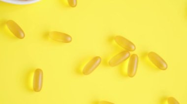 D vitamini ve Omega 3 balık yağı kapsülleri sarı arka planda kalp şeklinde bir tabakta. Sağlık hizmetleri kavramı. Üst görünüm