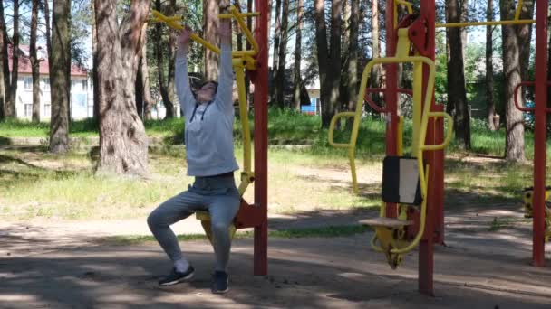 公園のストリートジムで体操をしている独身青年、ストリートワークアウト。外のフィットネス。Covid-19予防のための単独演習 — ストック動画