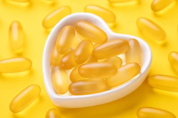 Κλείστε τα καψάκια Omega 3 σε πλάκα σχήματος καρδιάς σε κίτρινο φόντο. Μαλακό λάδι ψαριού. Έννοια της υγειονομικής περίθαλψης. Αντιγραφή χώρου. Άνω όψη — Φωτογραφία Αρχείου