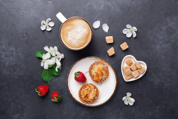 Kaffee mit Kuchen und Frühlingsblumen auf dunklem Steingrund. Ansicht von oben — Stockfoto