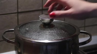 Kadın eli, çelik tavanın cam kapağını kaynar suyla açıyor. Seçici odak