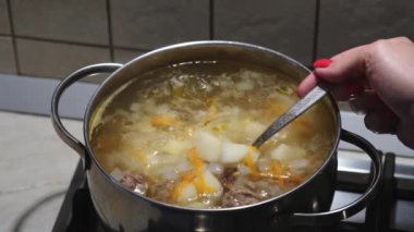 Sebzeli köfte çorbası pişirmek. Ev yapımı bulyon karıştıran kadın elleri. Yakın plan. Seçici odak