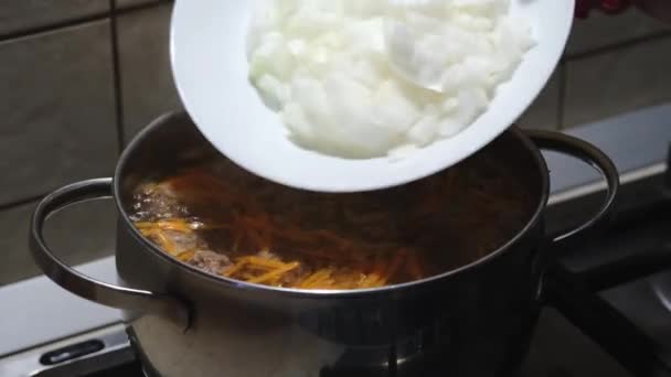 Matlagning av köttbullssoppa med grönsaker. Lägga lök i bouillon. Närbild. Selektiv inriktning — Stockvideo