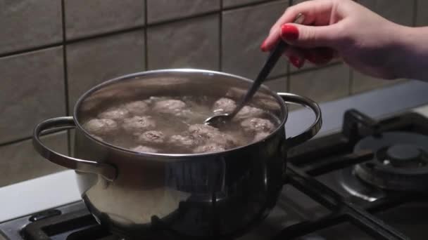 Tangan wanita mengaduk Bouillon dengan bakso. Proses persiapan sup. Fokus selektif — Stok Video