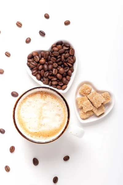 Kaffeebecher und herzförmige Teller mit Kaffeebohnen und braunem Zucker. Ansicht von oben. Vertikales Foto — Stockfoto