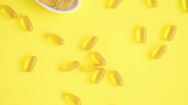 Omega 3 gélules dans une assiette en forme de cœur sur fond jaune. Huile de poisson softgels. Vue du dessus — Video