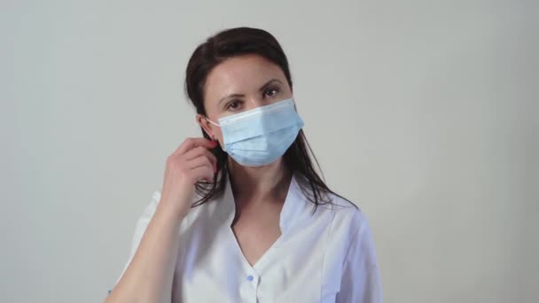 Retrato de una joven caucásica cansada doctora o enfermera poniéndose mascarilla médica. Concepto de prevención del Coronavirus. Movimiento lento — Vídeo de stock