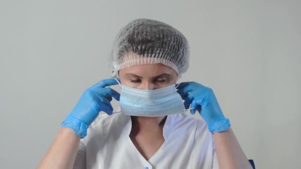 Retrato de jovem branco cansado médico feminino ou enfermeira colocando em máscara médica rosto. Conceito de prevenção de coronavírus. Movimento lento — Vídeo de Stock