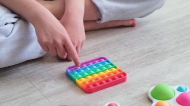 Çocuk gökkuşağı popit 'iyle oynuyor. Modern silikon oyuncak, trend 2021. Stres önleyici oyuncak patlat. Ağır çekim. Yakın plan.