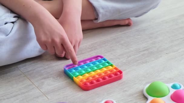 Kind spelen met regenboog pop. Modern siliconen speelgoed, trend 2021. Een anti-stress speeltje. Langzame beweging. Close-up — Stockvideo