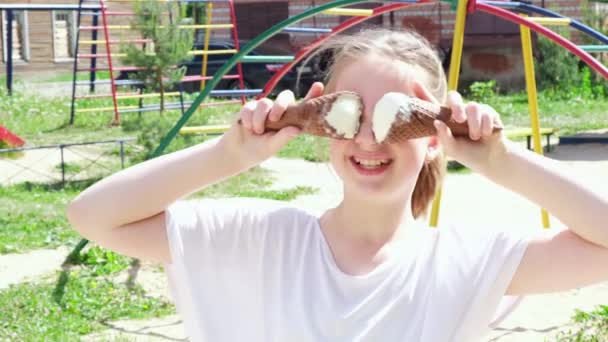 Retrato adolescente jugando con helado y sonriendo. Chica feliz comiendo delicioso helado en el parque de la ciudad. Día soleado de verano. Movimiento lento — Vídeo de stock
