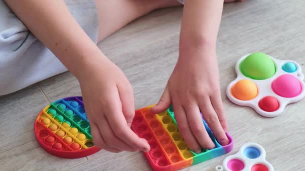 Barn leker med regnbågspopit. Modern silikonleksak, trend 2021. Antistress leksak pop den. Sakta i backarna. Närbild — Stockvideo