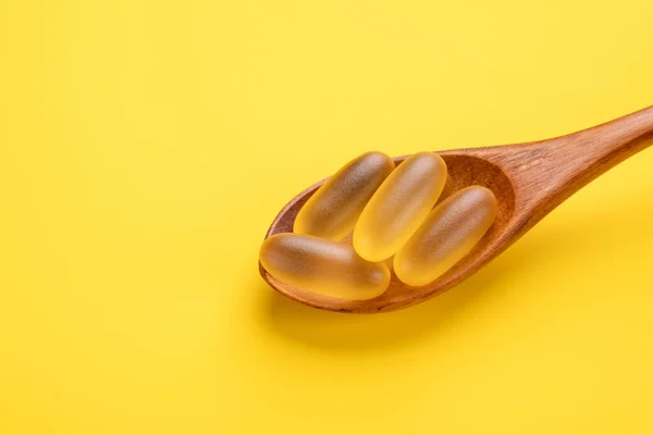 Omega 3 χάπια σε ξύλινη κουτάλα σε κίτρινο φόντο. Μαλακό λάδι ψαριού. Κλείσε. Αντιγραφή χώρου — Φωτογραφία Αρχείου