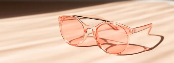 Modne różowe okulary przeciwsłoneczne na beżowym tle. Letnia koncepcja sprzedaży. Baner poziomy — Zdjęcie stockowe