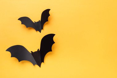 Sarı arka planda uçan siyah yarasalar. Metnin için kopya alanı olan Cadılar Bayramı tebrik kartı