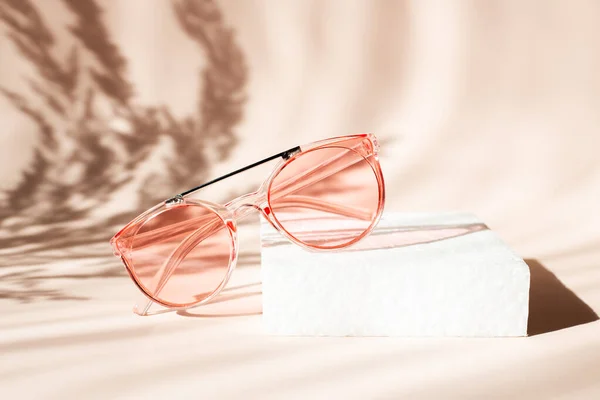 Modne różowe okulary na podium geometrycznym. Pampas trawa naturalne cienie na beżowym tle. Pojęcie sprzedaży letniej — Zdjęcie stockowe
