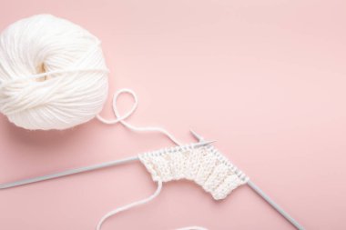 Beyaz örgü yünü ve pastel pembe arka planda örgü iğneleri. Hobi örgü. Üst Manzara. Boşluğu kopyala