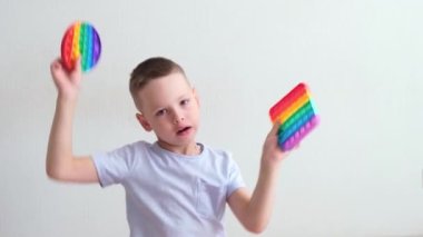 Küçük çocuk evde gökkuşağı popitle oynuyor. Modern silikon oyuncak, trend 2021. Stres önleyici oyuncak patlat. Yavaş çekim