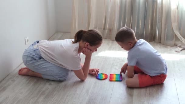 Pojke och gril trycker bubblor på morden silikon leksak pop den. Anti stress sensoriska leksaker popit och enkel dimple. Närbild. Långsamma rörelser — Stockvideo