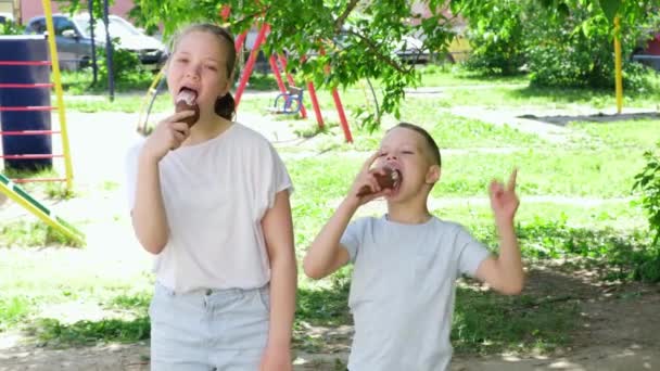 Щасливі милі діти їдять смачне морозиво. Брат і сестра з морозивом на відкритому повітрі. Літній сімейний спосіб життя. Сонячний літній день. Повільний рух — стокове відео