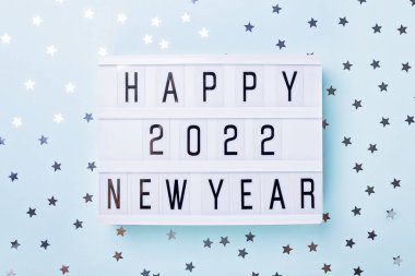 Mavi arka planda Mutlu Yıllar 2022 yazılı ışık kutusu. Üst Manzara. Yeni yıl kutlaması. Mutlu yıllar 2022 kavramları