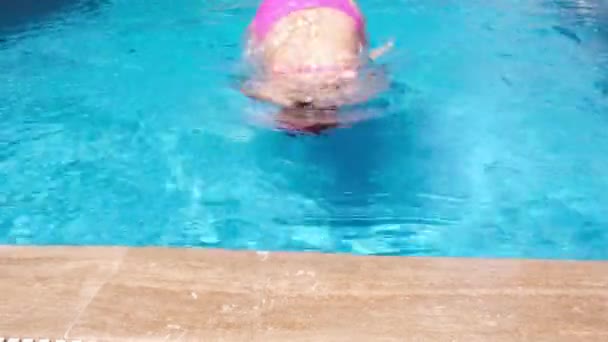 Leuk meisje met roze waterglazen in het zwembad. Meisje dat uit het water komt — Stockvideo